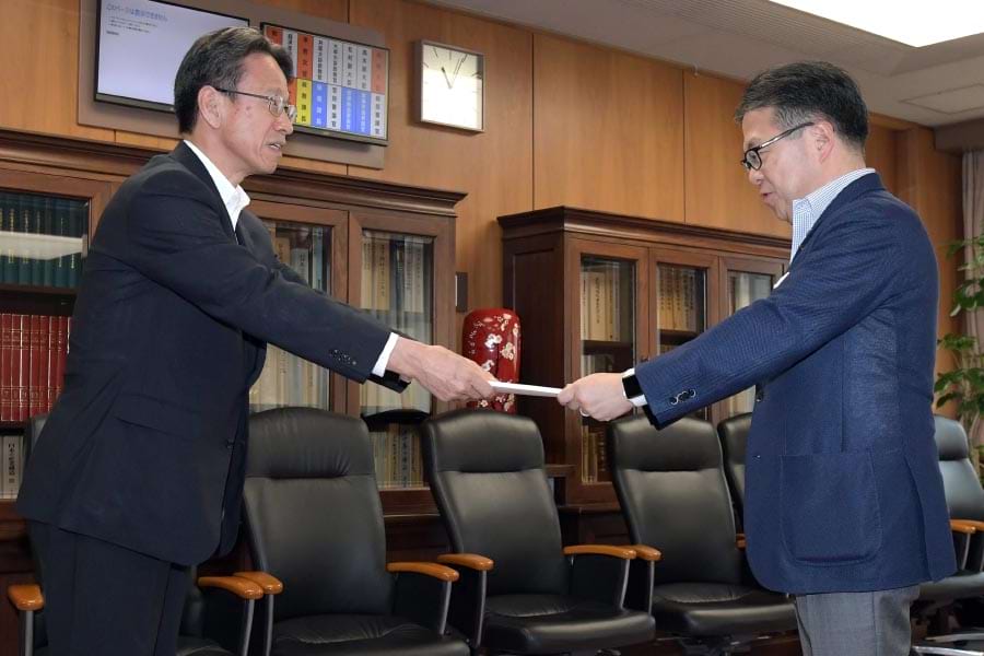 世耕経産相(右)に届出書を提出する岩根社長(6日、東京・霞が関)