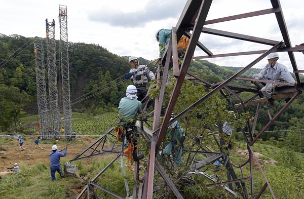 送電設備にも深刻な被害が発生した。岩知志線（６万６０００Ｖ）では地滑りによって鉄塔が２基倒壊。写真は１２日、倒壊した岩知志線の鉄塔から仮鉄柱へ移線する作業員（むかわ町）