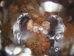 燃料デブリとみられる堆積物。左右両端に見えるのは調査機器の先端部(13日、東電HD提供)